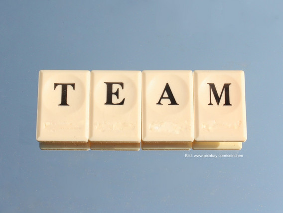 Das Wort "TEAM" buchstabiert mit Steinchen, auf welchen die Buchstaben stehen.